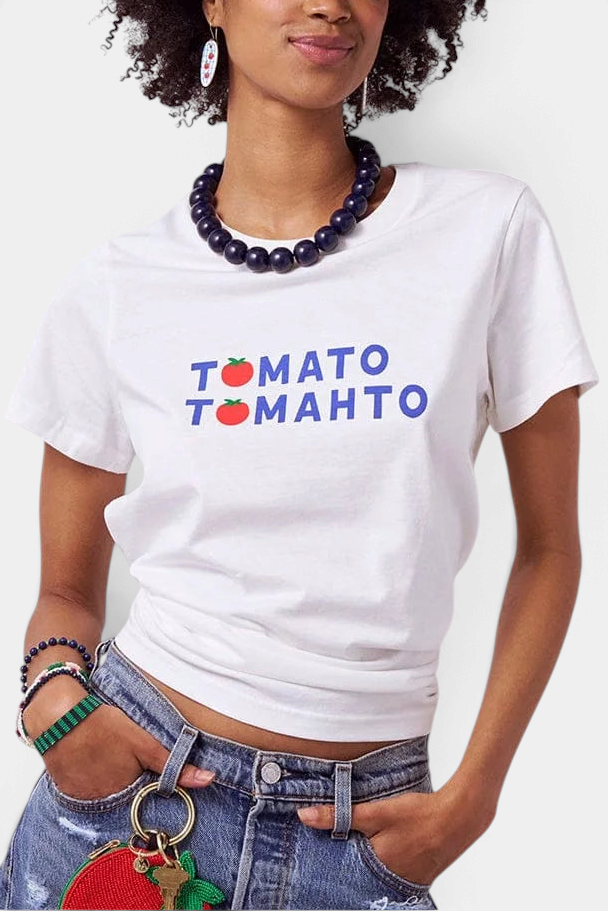 The Copper Shed white graphic t-shirt featuring Tomato Tomahto text and red tomato icons worn by a woman
