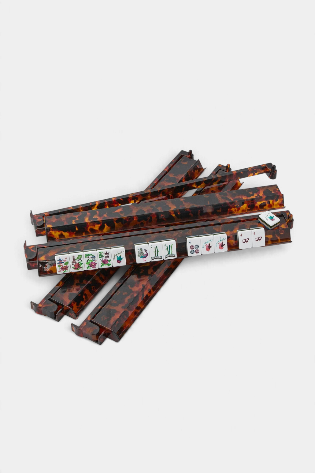 The Copper Shed tortoise shell acrylic mahjong racks with attached pushers and game tiles on a white background.