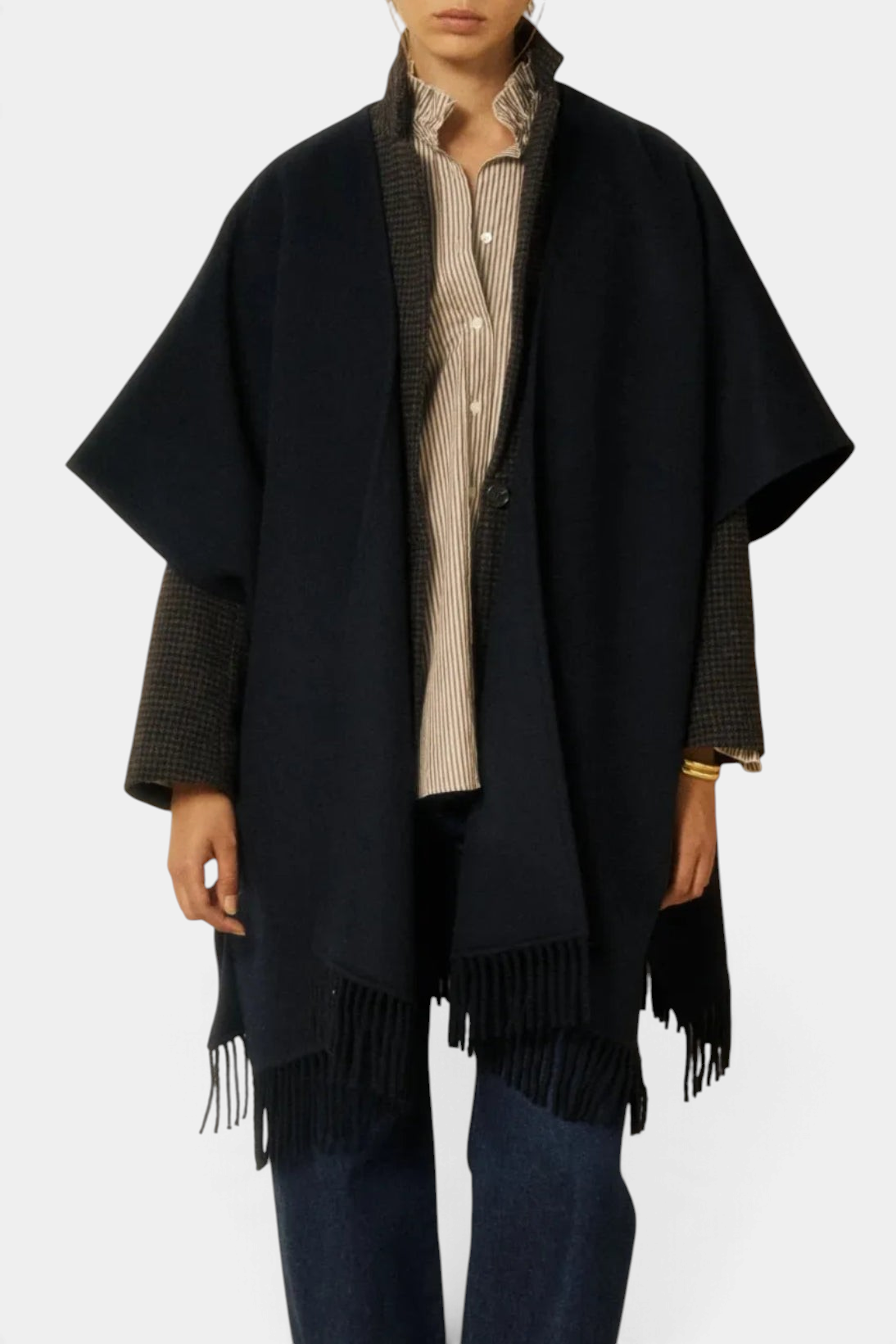 The Copper Shed Virginie cape in navy double-faced wool with fringe trim worn over a striped shirt and blazer