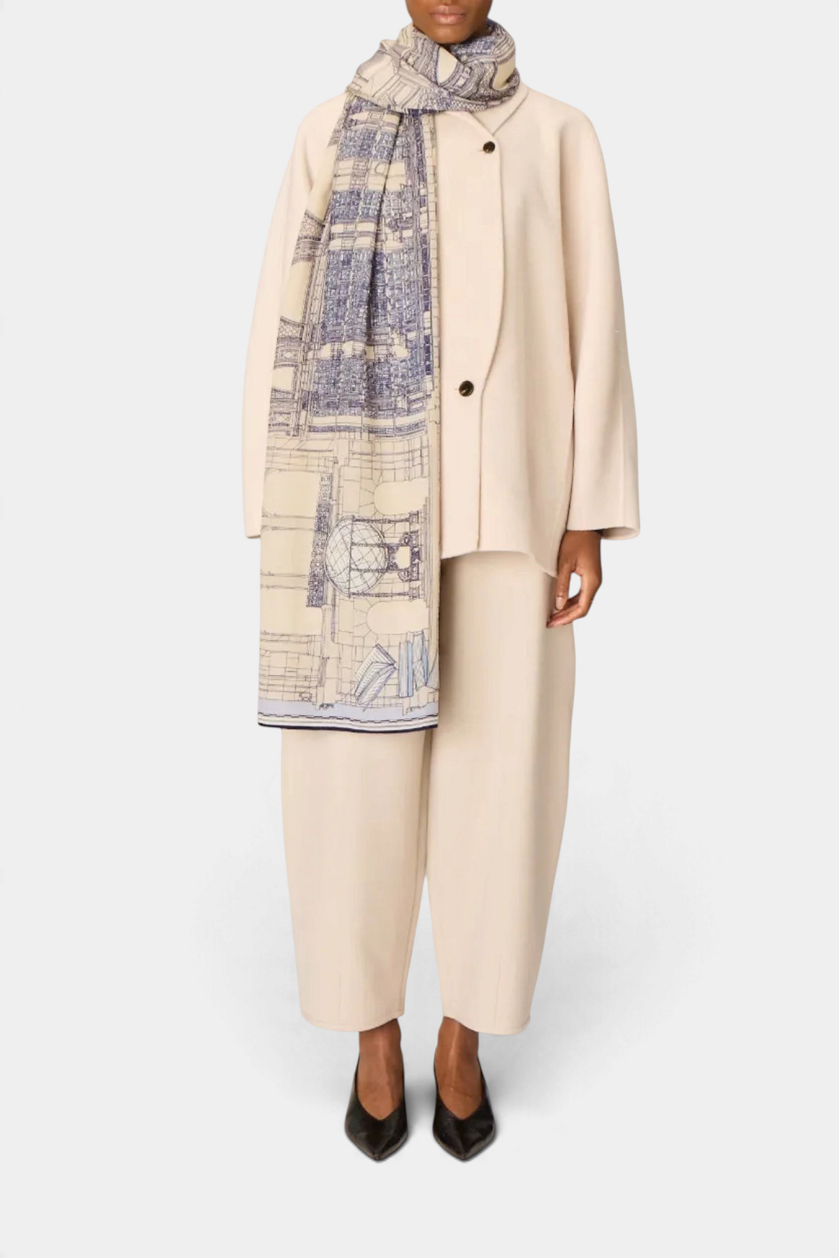 The Copper Shed Vivienne grey wool scarf featuring a detailed architectural print worn over a cream suit