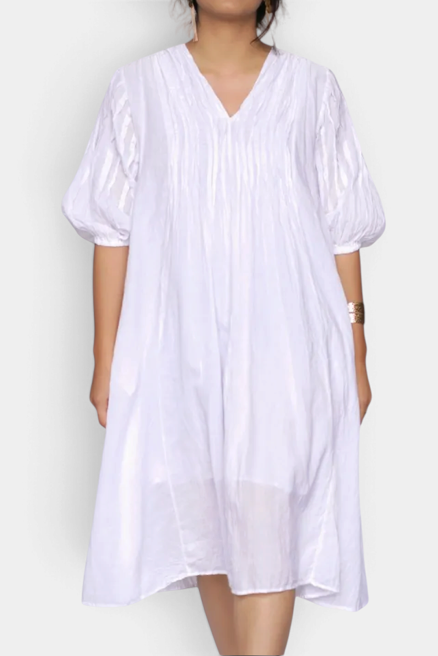 The Copper Shed Skye white cotton gauze dress with pin-tucked neckline, puff sleeves, and A-line silhouette.