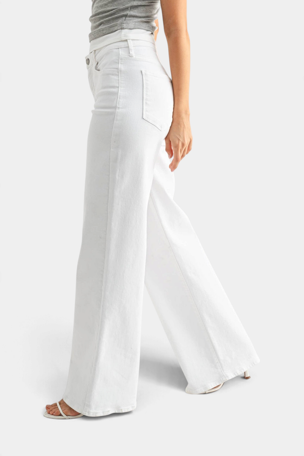 The Copper Shed white stretchy wide leg jeans worn by a model in a side profile view against a plain background