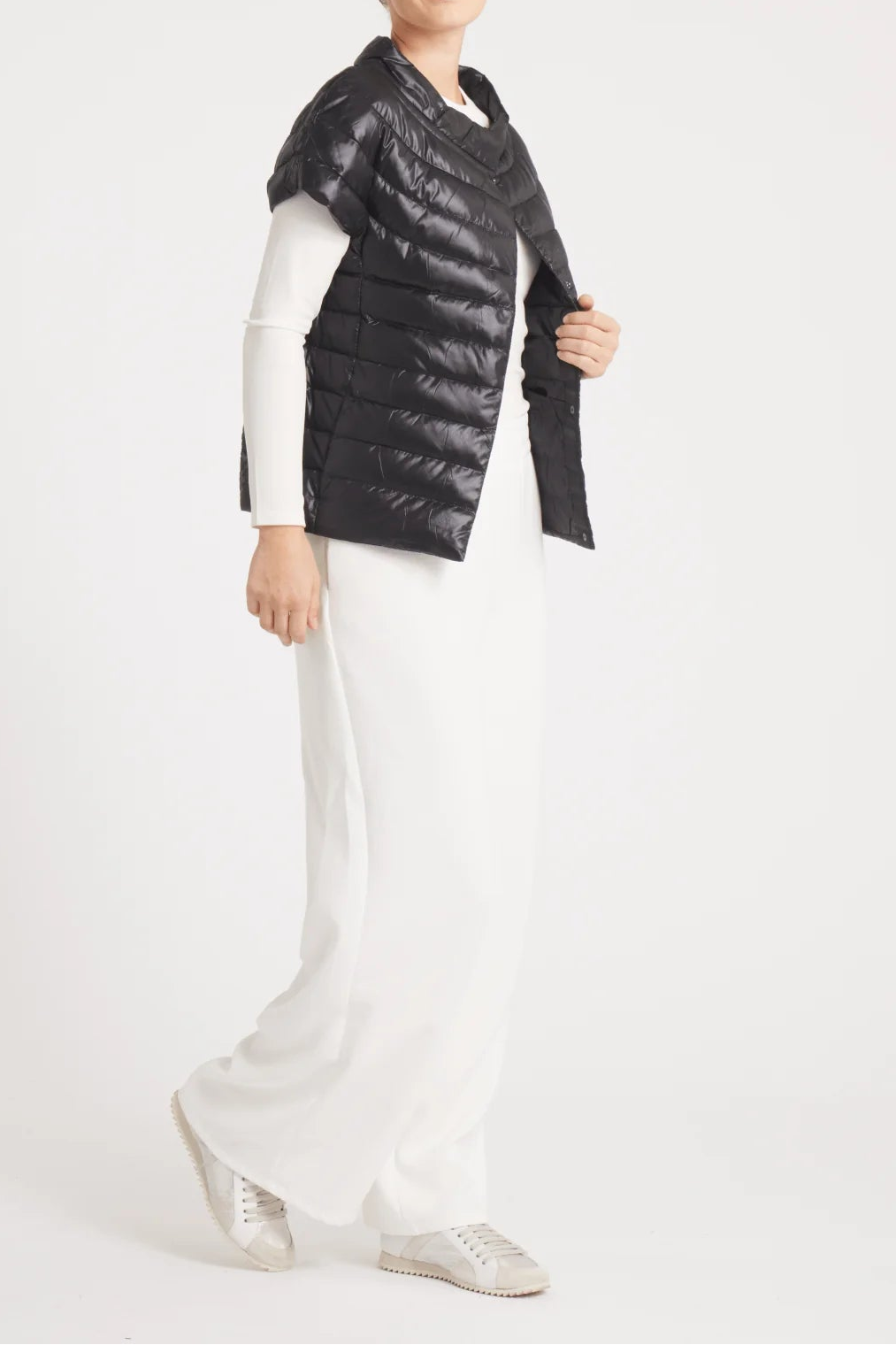 Person wearing a black puffer vest over a white outfit on a white background