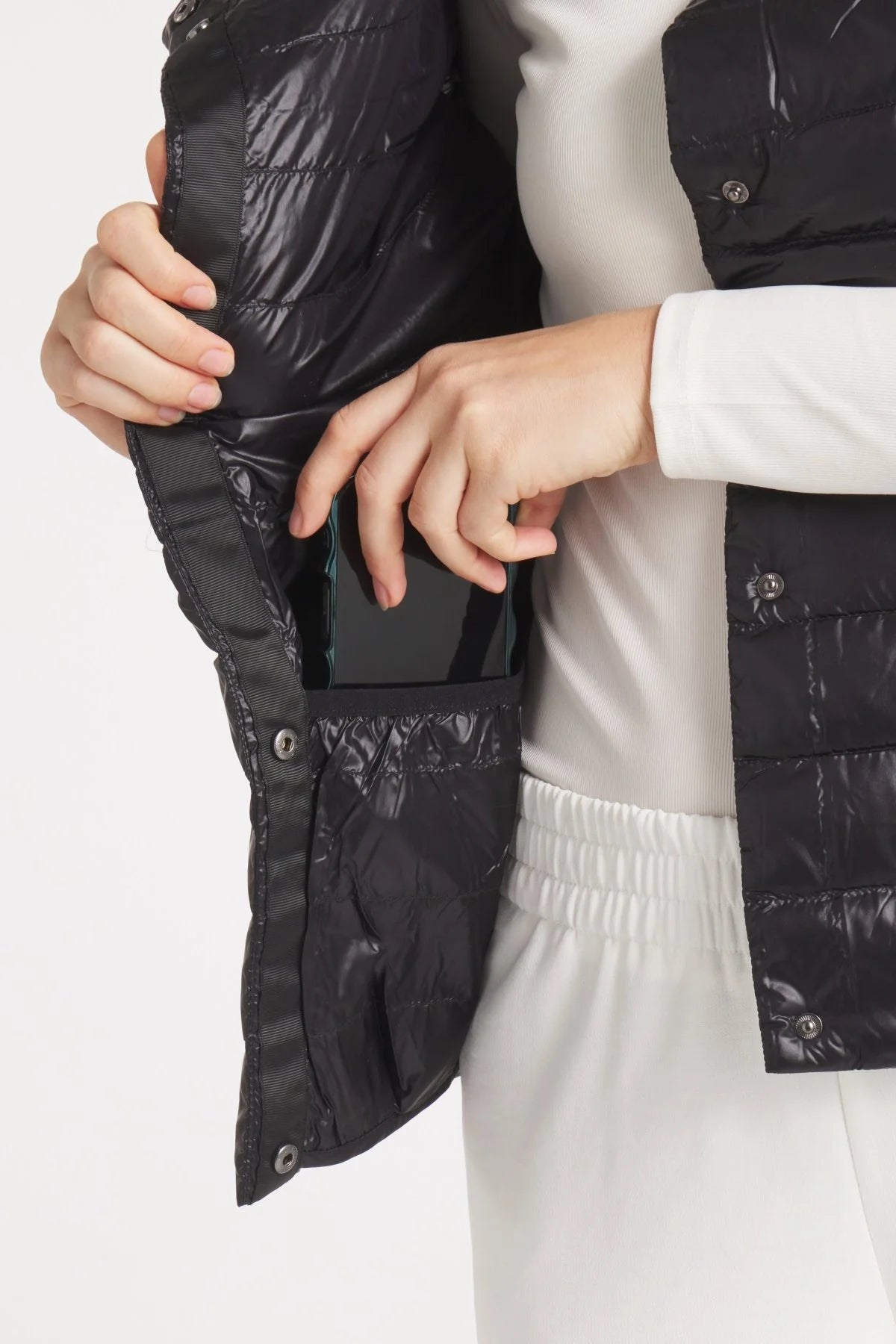 Person wearing a black quilted jacket on a white background
