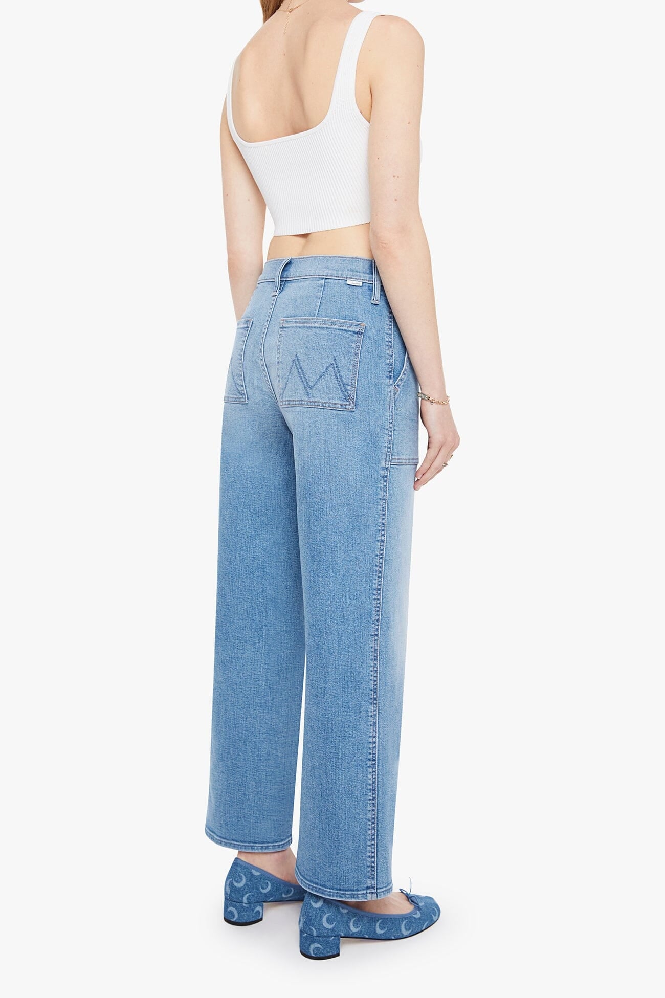 Person wearing light blue jeans and a white top on a white background