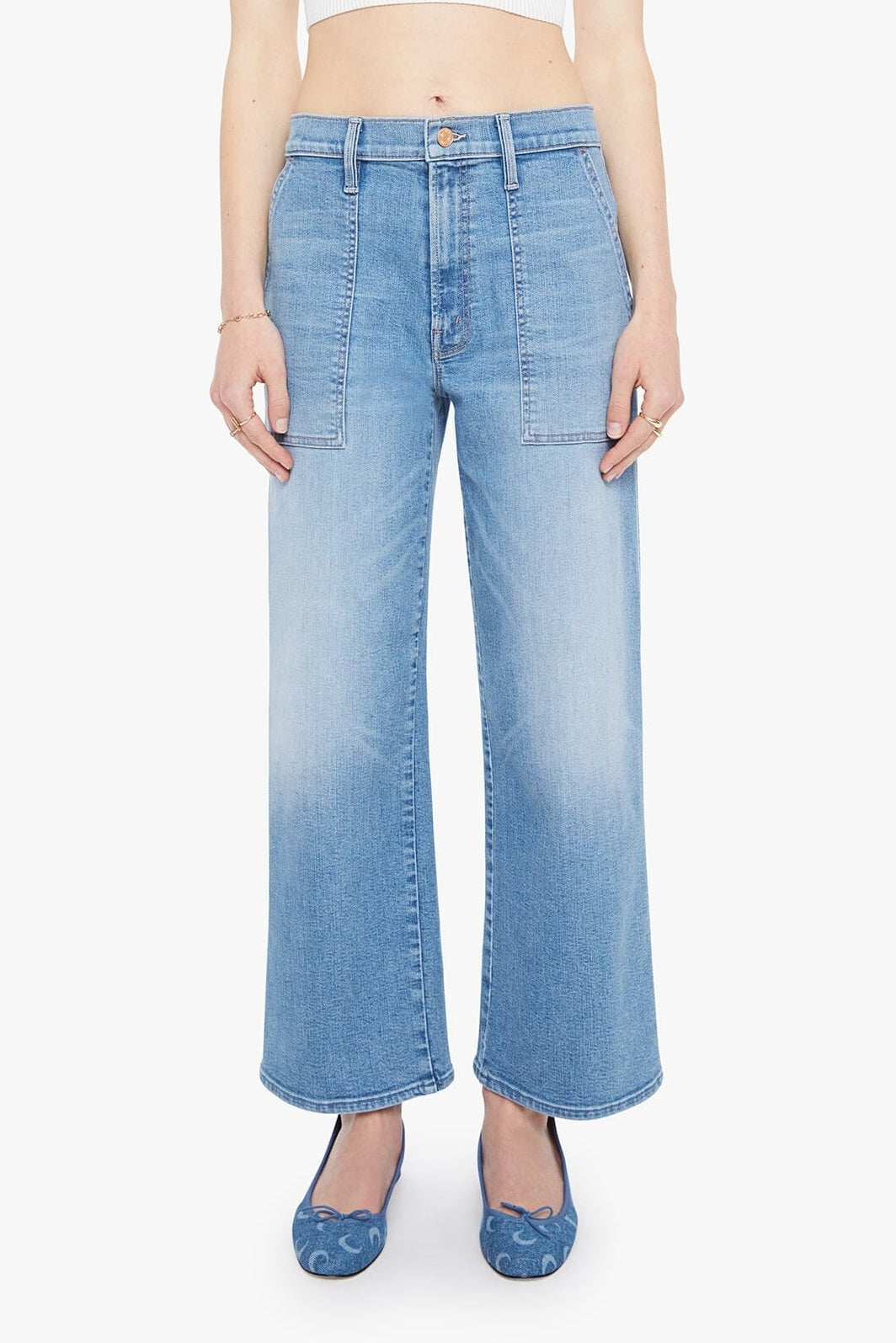 A model wearing light blue wide-leg cropped jeans with a vertical ombre fade from medium blue at the top to a very light washed blue at the hem, paired with a white crop top and blue patterned flats.