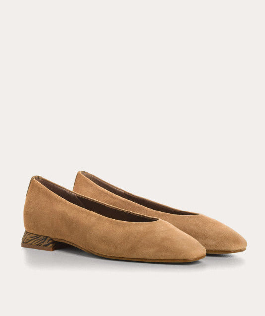Pair of brown suede shoes on a light beige background